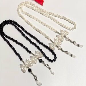 Eyeglass necklace holders, one black and  white and one white